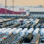 Extensive car storage lot at a BYD facility, rows of parked cars with a BYD building in the background